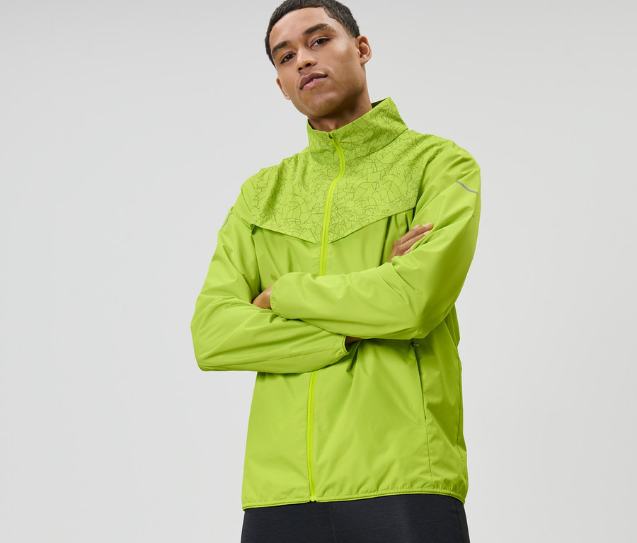 Mann mit verschränkten Armen trägt neonlime Windprotection-Laufjacke.
