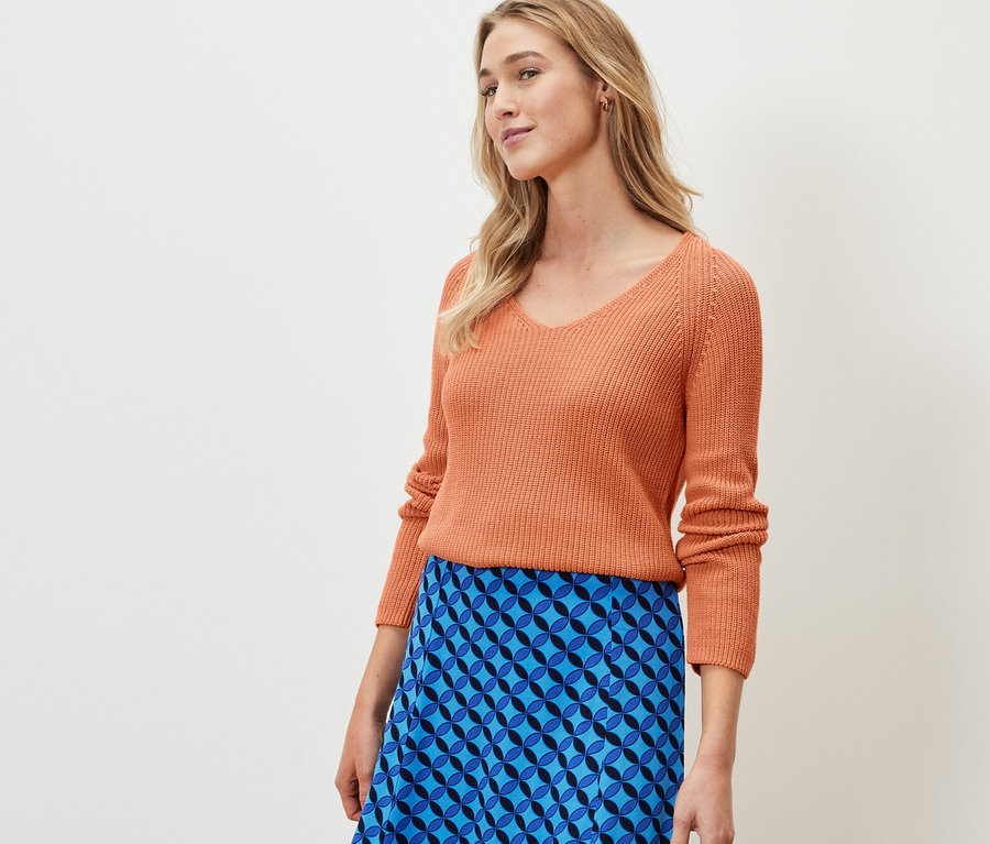 Frau trägt einen peachfarbenen Strickpullover.