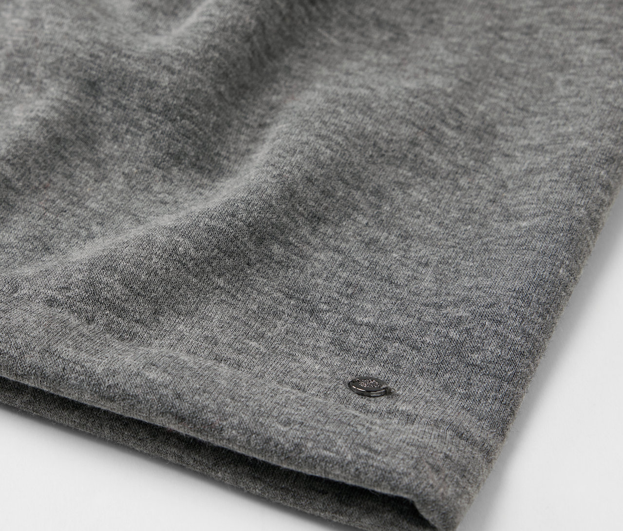 Detailaufnahme eines grauen Stoffes mit kleinem Logo.