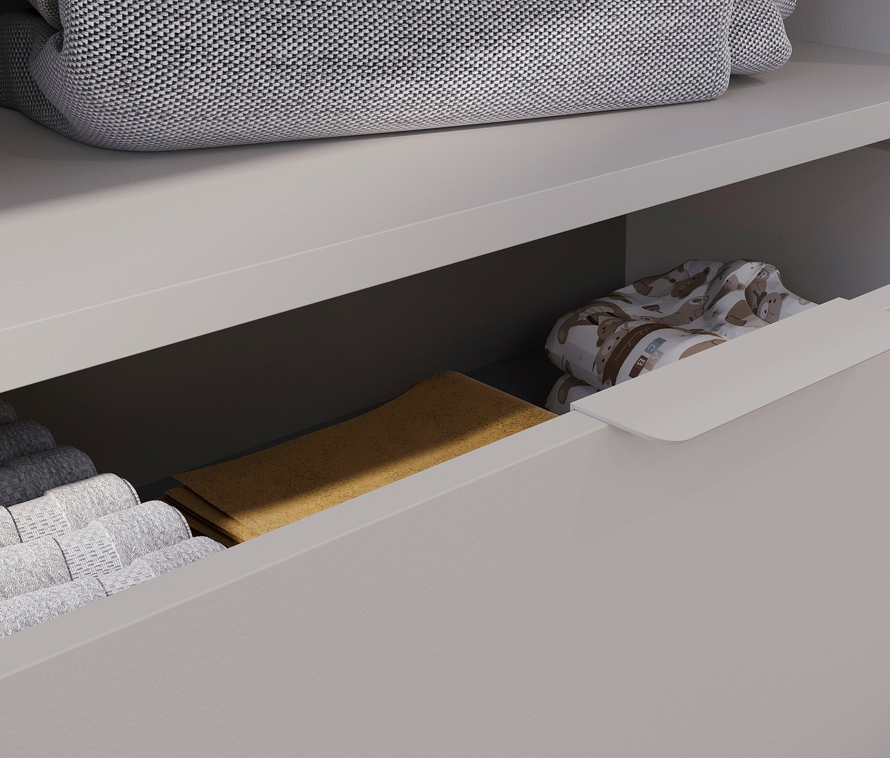 Offene Schublade der breiten Wickelkommode »Alkmaar« mit gefalteten Handtüchern und Kleidung.