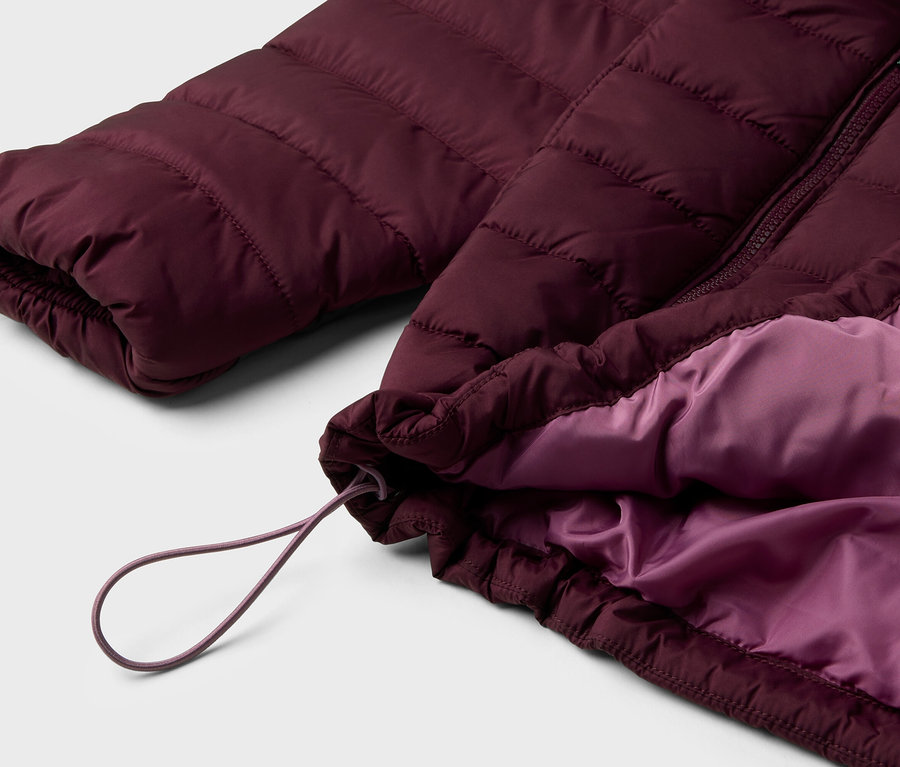 Detail einer bordeauxroten Steppjacke mit lila Futter und Kordelzug.