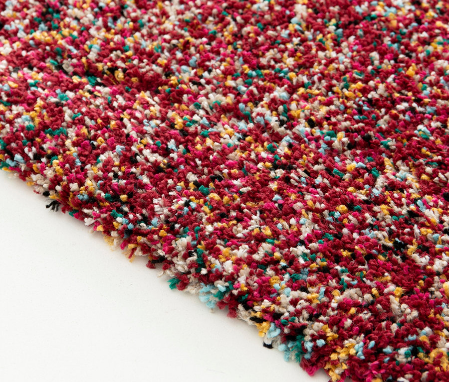 Nahaufnahme des Teppichs »Relic« in Autumn Spice mit roten, weißen, gelben, grünen und schwarzen Flecken auf weißem Grund.