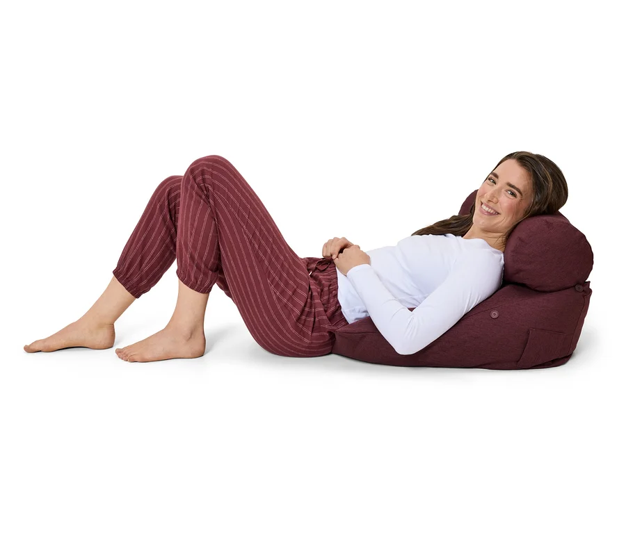 Eine Frau liegt auf einem Sitzsack in gestreifter Hose und lächelt.