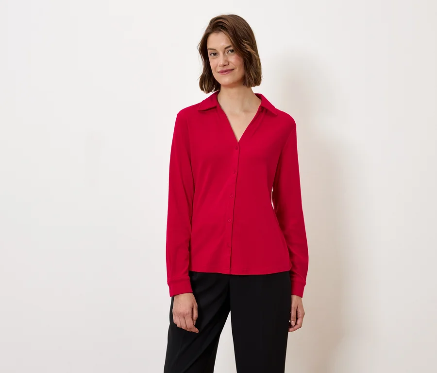 Frau trägt eine rote Bluse und schwarze Hose.