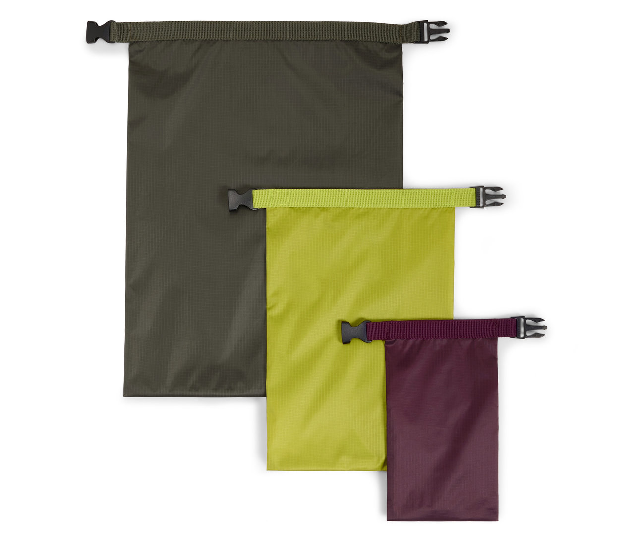 Drei wasserdichte Packsäcke in verschiedenen Größen und Farben (Olive, Limette, Lila) liegen auf einem weißen Hintergrund.