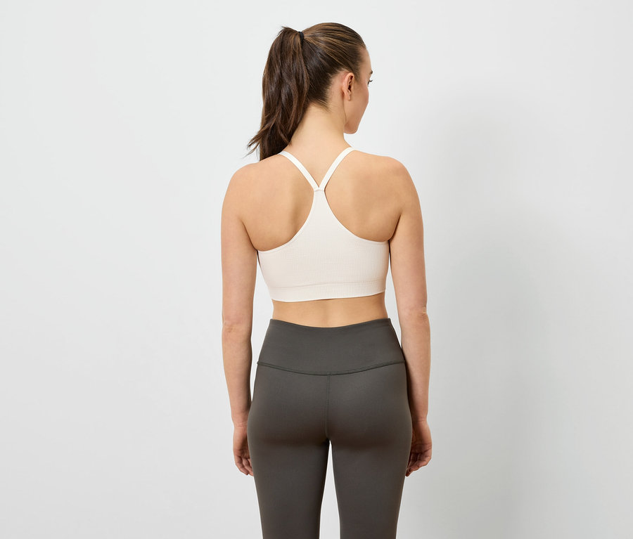 Frau von hinten trägt einen Sport-BH und Leggings.