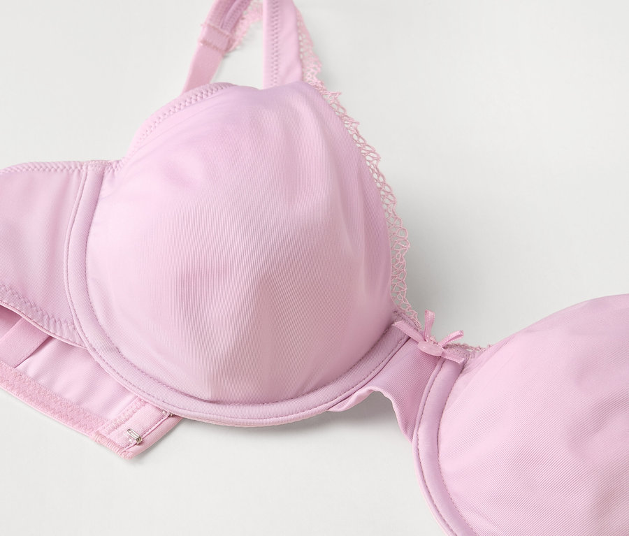 Detailaufnahme eines hellrosa Bügel-BHs mit Spitze.