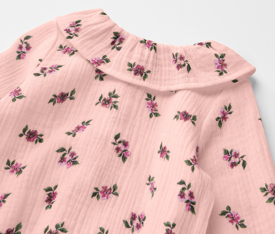 Detailansicht eines Baby-Musselin-Bodys mit Blumenmuster.