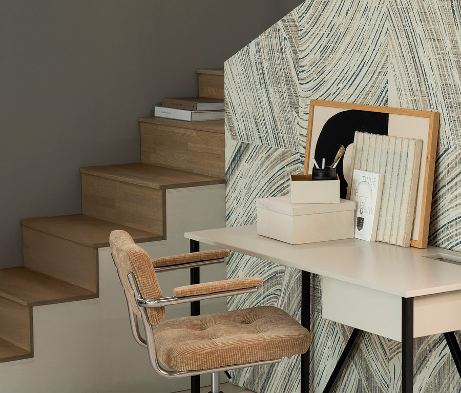 Ein WOOOD »Kova« Bürostuhl steht vor einem Schreibtisch, neben einer Treppe mit Büchern und Dekoration.