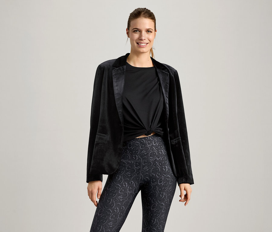 Frau trägt ein schwarzes Sportshirt und einen schwarzen Blazer.