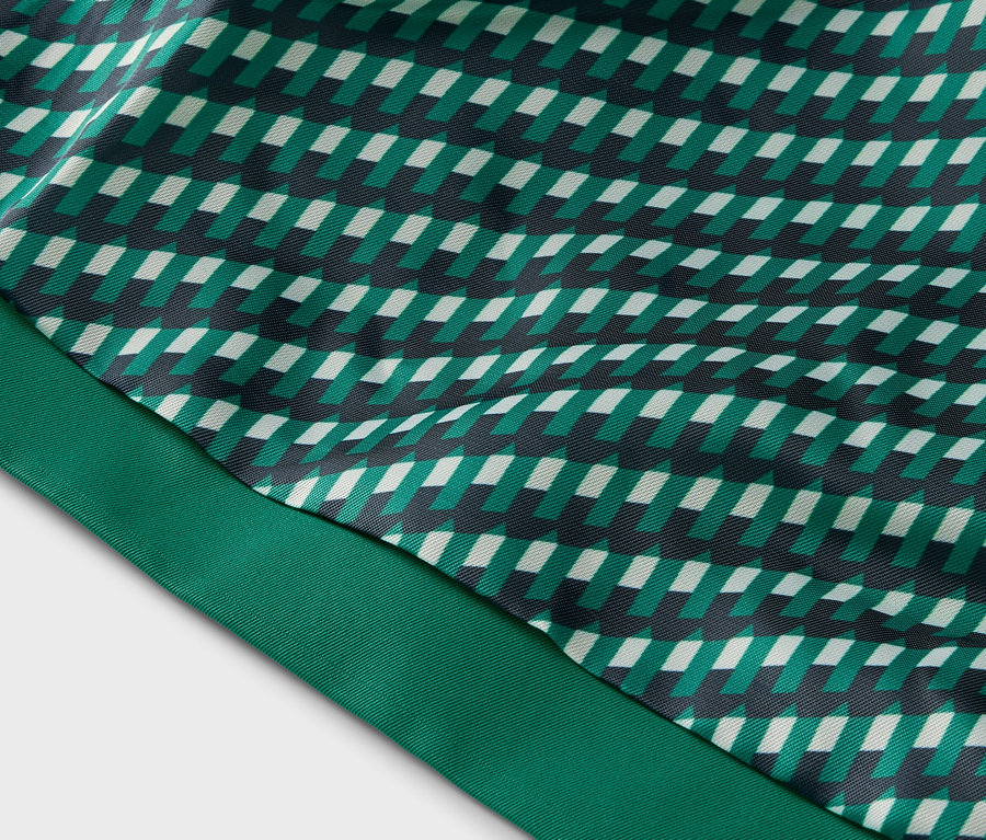 Nahaufnahme eines Stoffes mit geometrischem Muster in Grün-, Weiß- und Schwarztönen und einem grünen Band.