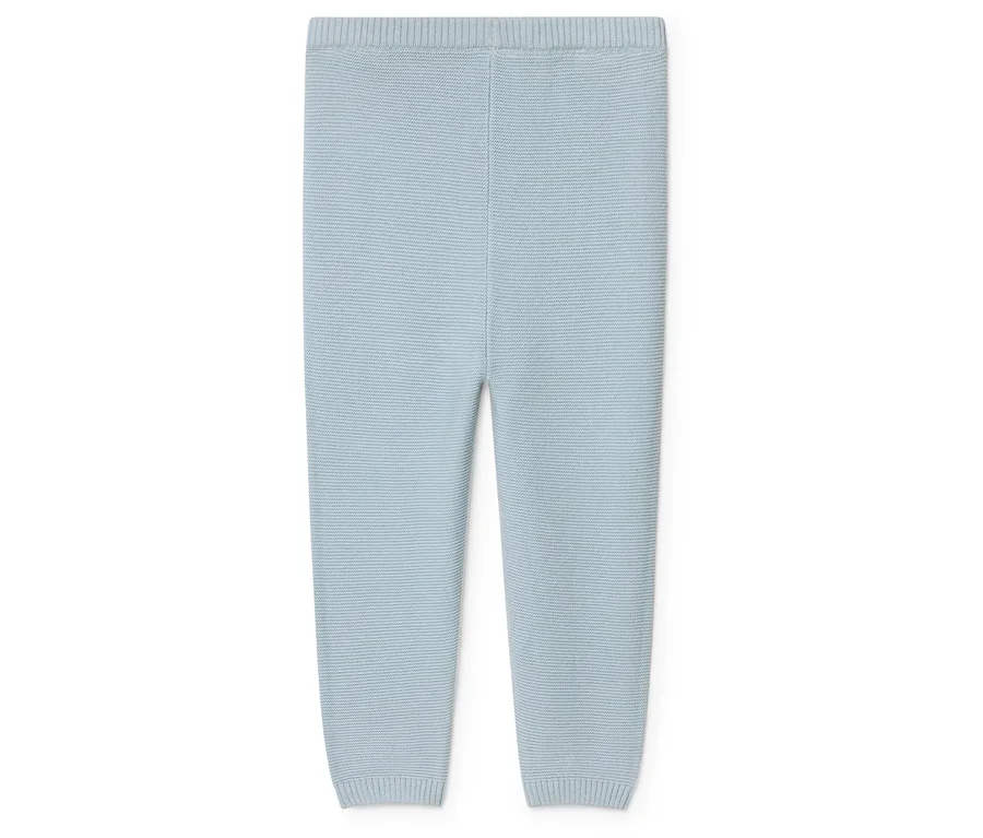 Hellblaue, gestrickte Babyhose liegt auf einem weißen Hintergrund.