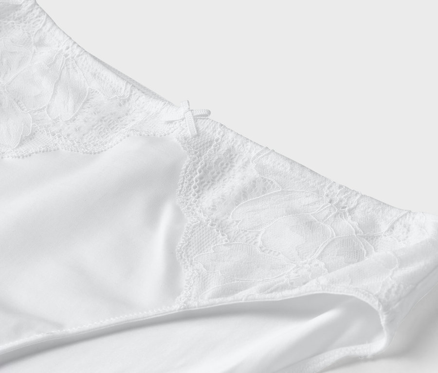 Detailansicht eines weißen Slips mit Spitzendetails und einer kleinen Schleife.