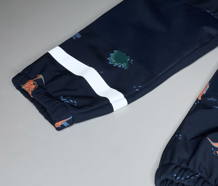 Nahaufnahme von marineblauen Hosenbeinen mit Dinosaurier-Muster und weißem Streifen auf grauem Hintergrund.