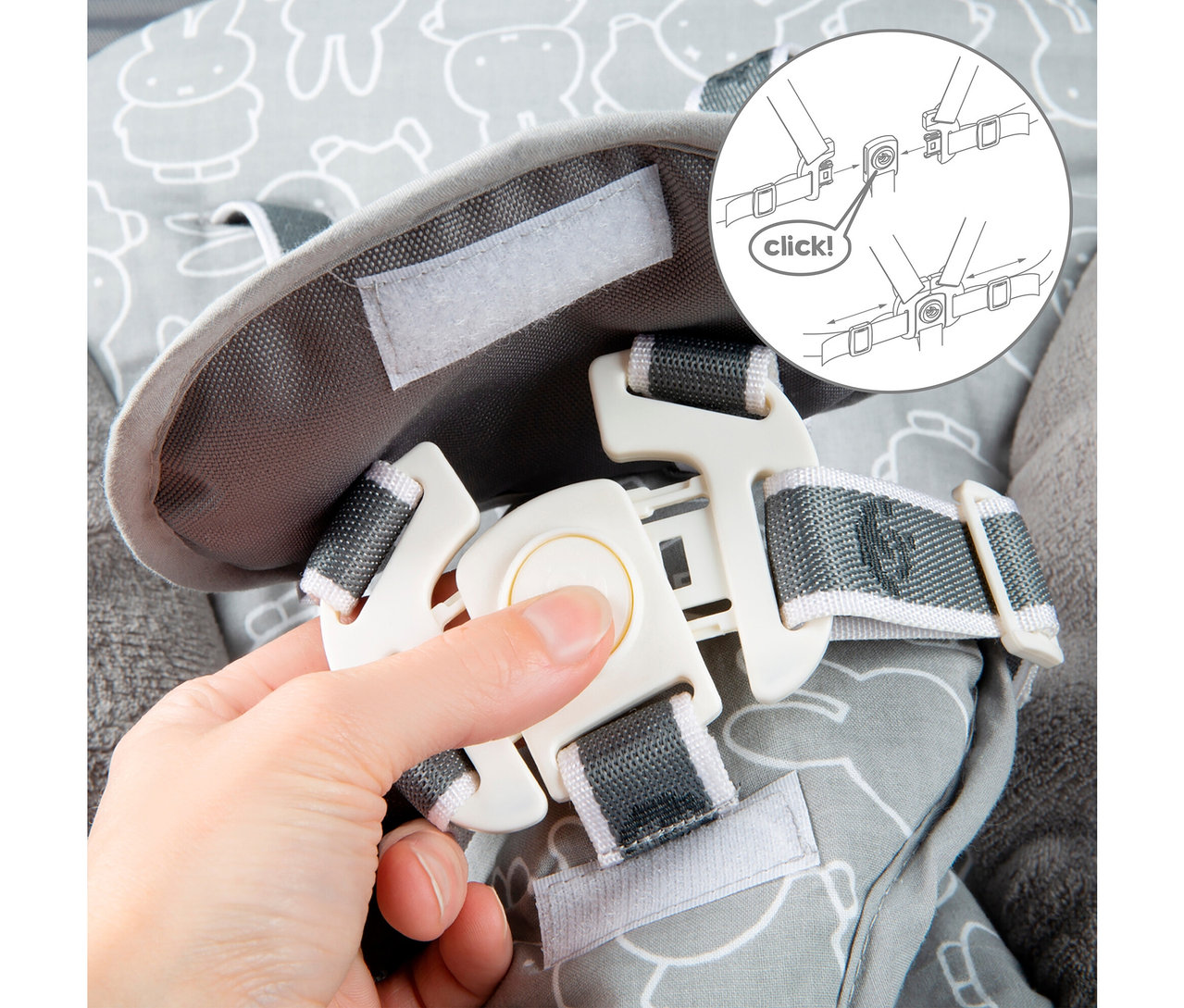 Eine Hand schließt einen weißen Plastiksicherheitsgurt über einem grauen Stoff mit einem Cartoon-Design.