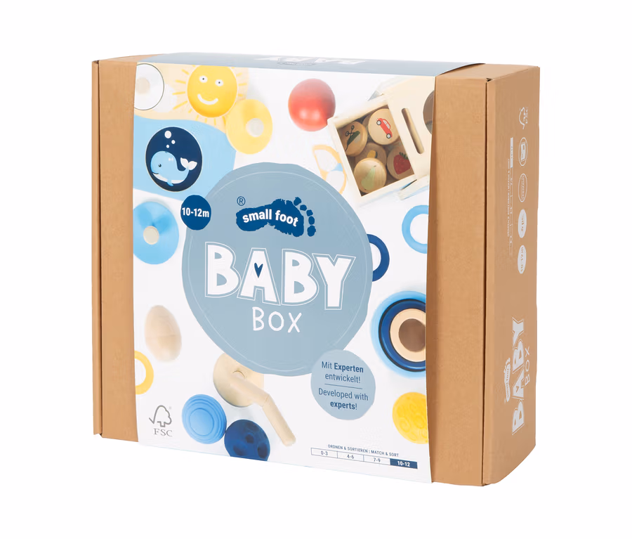 Brauner Karton der small foot Baby-Box für 10–12 Monate, mit Abbildungen von Holzspielzeug wie Sonne, Wal, Ringen und einer Sortierbox.