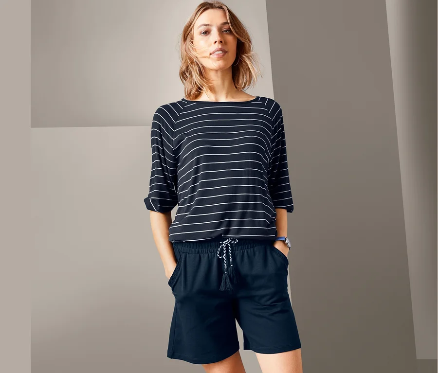 Frau steht mit Händen in den Taschen ihrer Jerseyshorts.