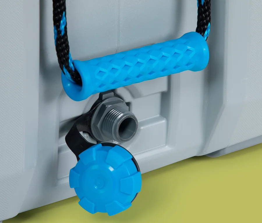 Detailaufnahme einer grauen Lifetime-Premium-Kühlbox mit blauem Griff und Ablassventil vor gelbem Hintergrund.