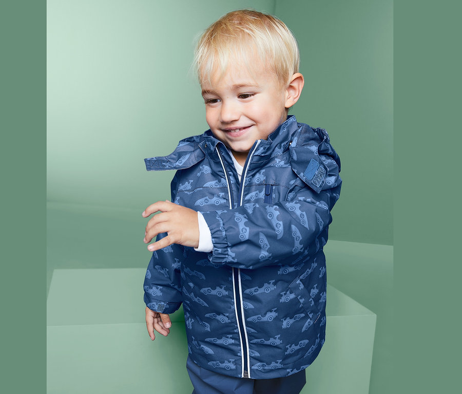 Ein Junge trägt eine blaue Regenjacke mit Automobilmuster.