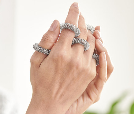 Frau massiert ihre Finger mit Finger-Massageringen.