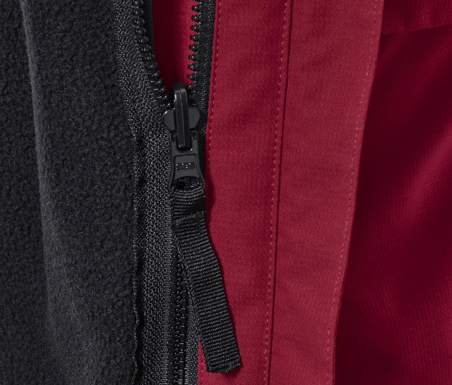 Detailansicht eines Reißverschlusses einer Outdoorjacke mit schwarzem Fleecefutter und rotem Außenmaterial.