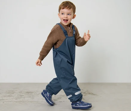 Junge geht, trägt eine dunkelblaue Kinder-Thermo-Regenhose.