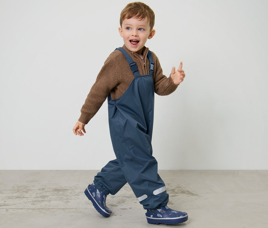 Junge geht, trägt eine dunkelblaue Kinder-Thermo-Regenhose.