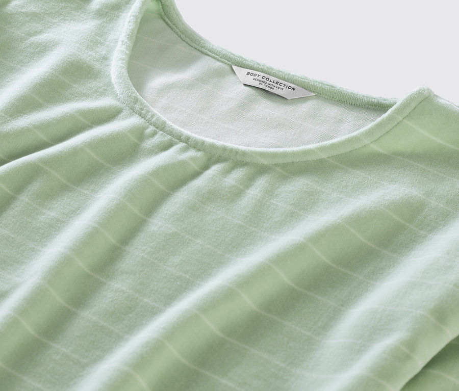 Detailaufnahme eines grünen Nicki-Pyjamas mit weißen Streifen.