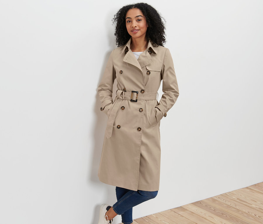 Frau posiert in beige Trenchcoat.