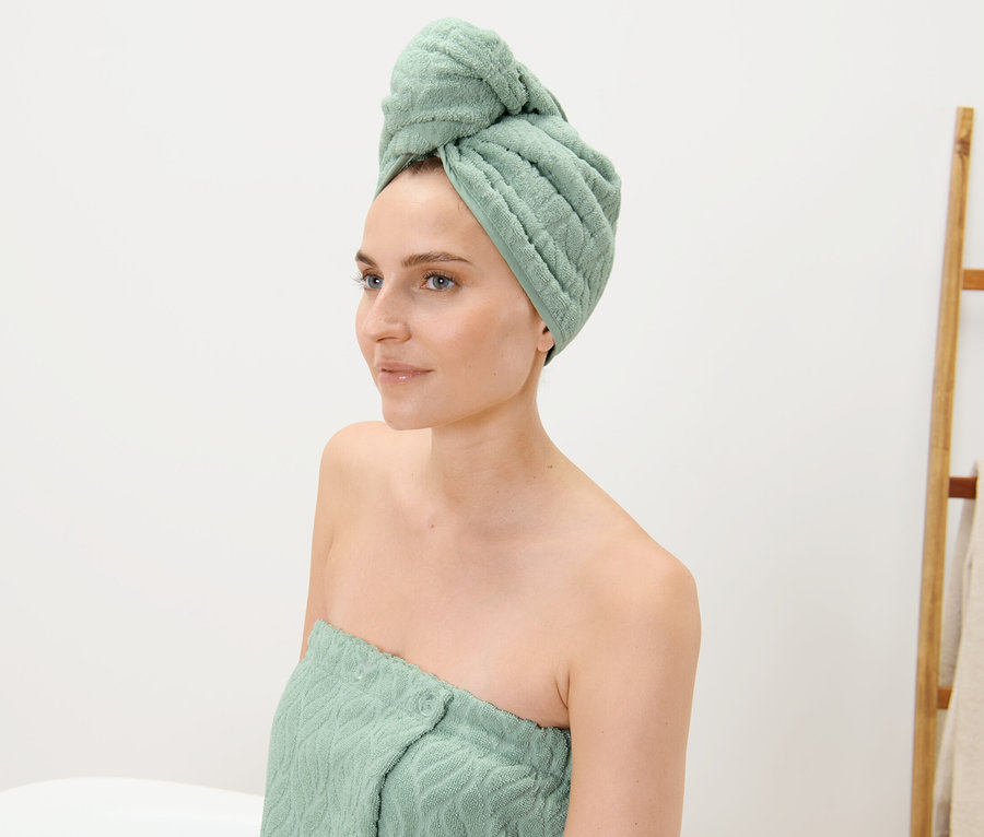 Frau mit Turban-Handtuch auf dem Kopf und einem Handtuch um ihren Körper gewickelt.
