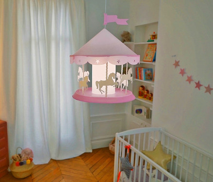In einem Zimmer hängt eine rosafarbene Karussell-Deckenlampe »Karussell« mit Pferden.
