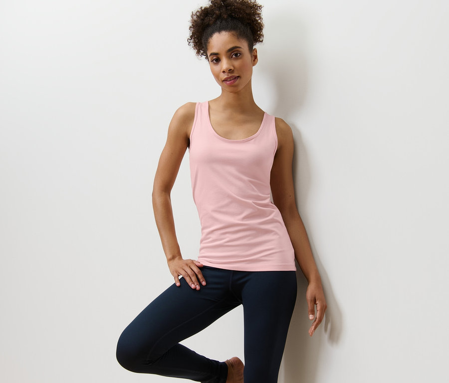Frau posiert in einem roséfarbenen Top aus einem 2er-Set.