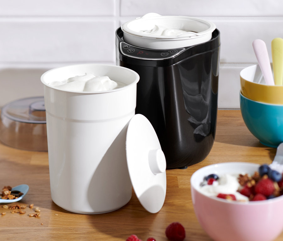 Joghurt und Müsli auf einem Tisch mit einem Joghurt- und Frischkäsebereiter.