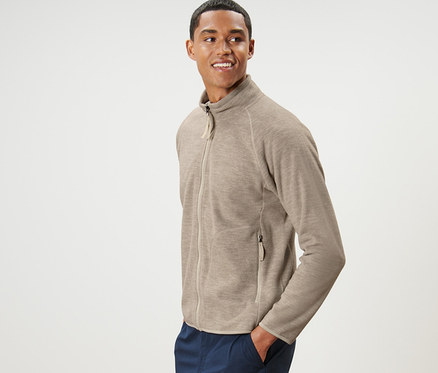 Mann posiert in beige Fleecejacke und marineblauer Hose.