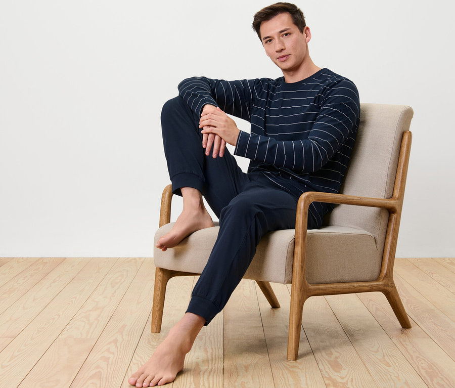 Mann sitzt im Sessel und trägt einen Pyjama.
