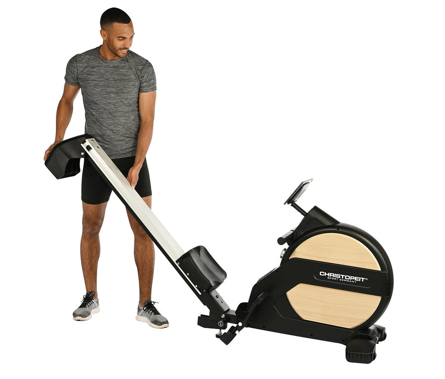 Mann hält Teil des Rudergeräts »Ergometer Vico«.