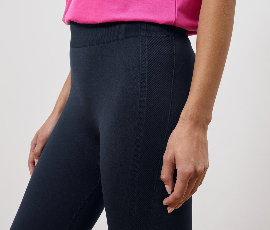 Frau trägt Leggings und ein pinkes Oberteil.