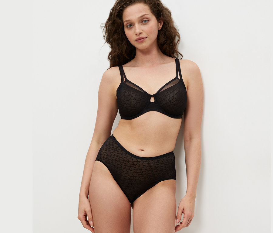 Frau trägt schwarzen Triumph Signature Sheer Minimizer und schwarze Unterhose.