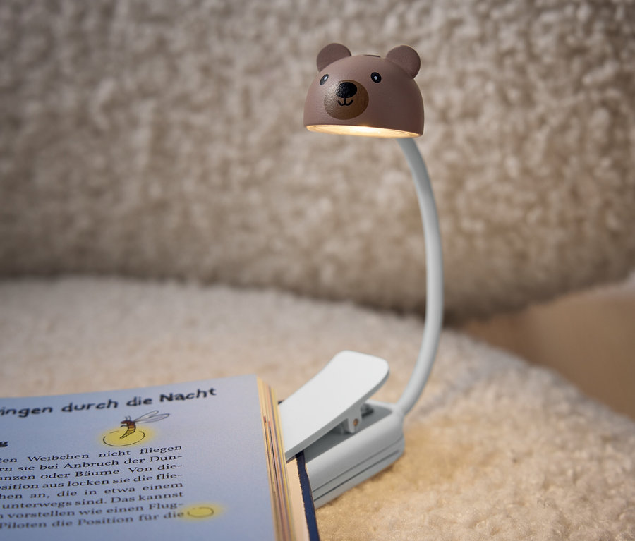 Eine Bären-förmige Leselampe ist an einem Buch befestigt.