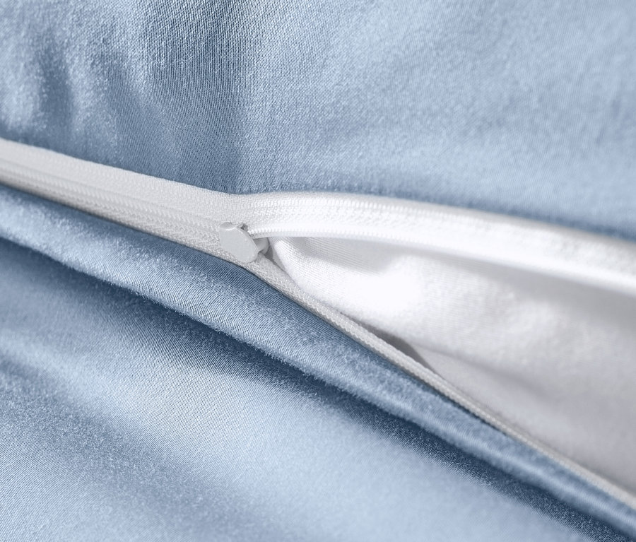 Detailansicht von hellblauer Baumwollsatin-Bettwäsche mit weißem Reißverschluss.