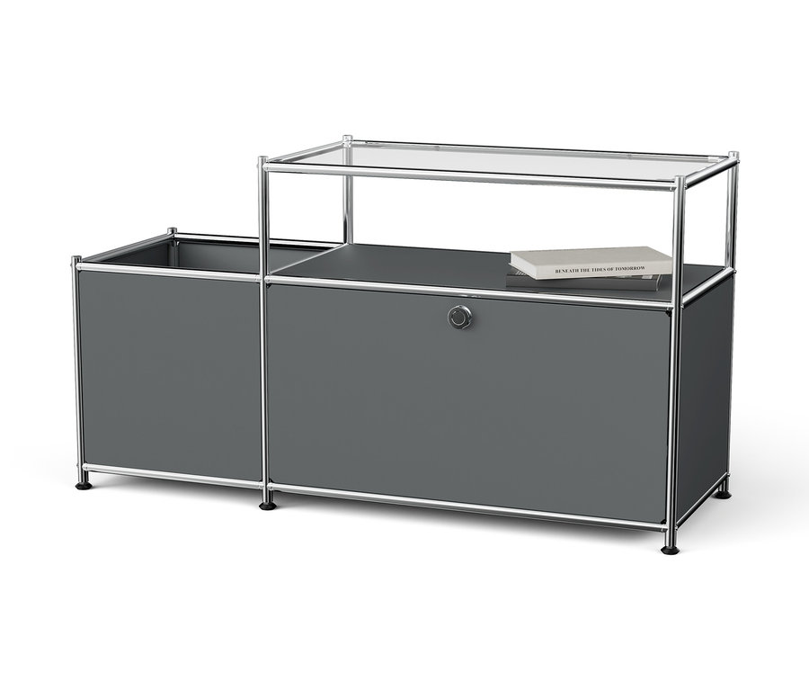 Graues Aufbewahrungssystem mit Chromrahmen und Glasplatte, auf der ein Buch liegt.