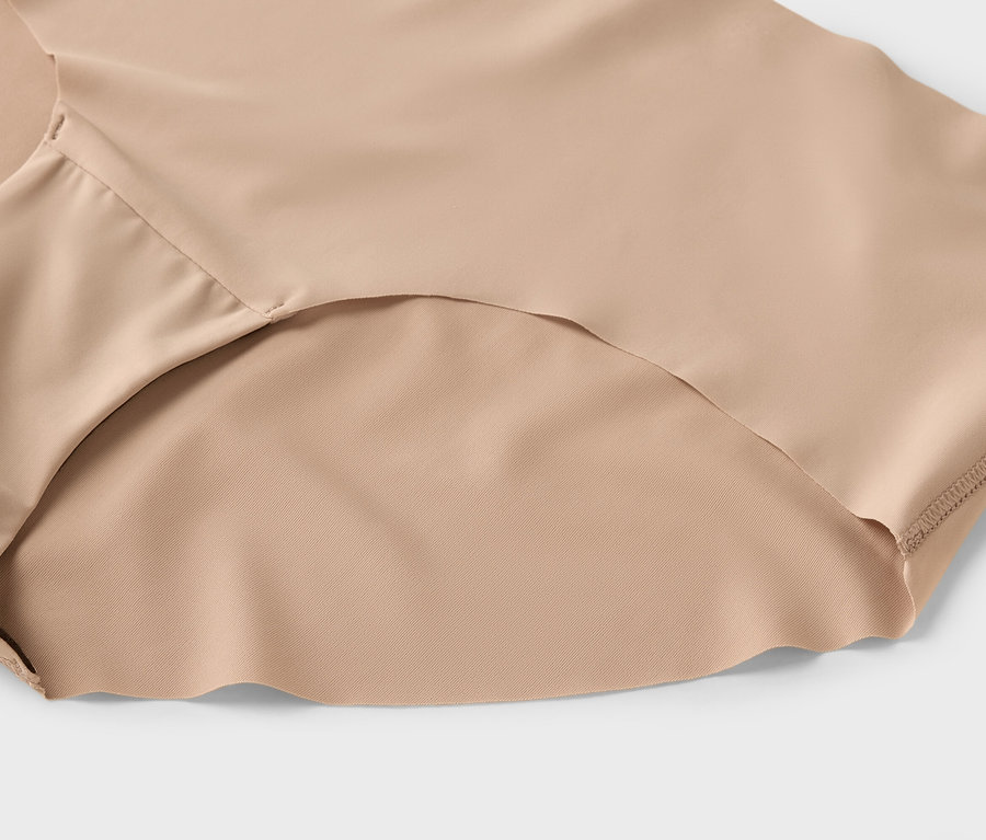 Nahaufnahme von beiger Damenunterwäsche auf hellgrauem Hintergrund.