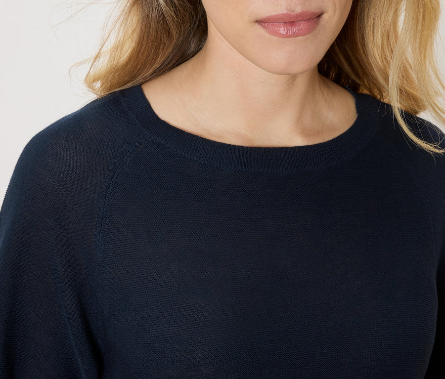Nahaufnahme einer Frau, die einen marineblauen Pullover trägt.