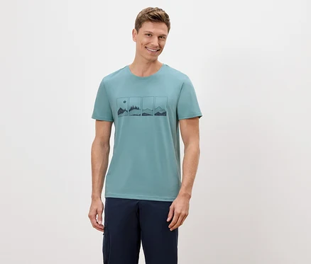 Mann trägt ein grünes T-Shirt mit einer Grafik von Bergen und einer Sonne darauf.