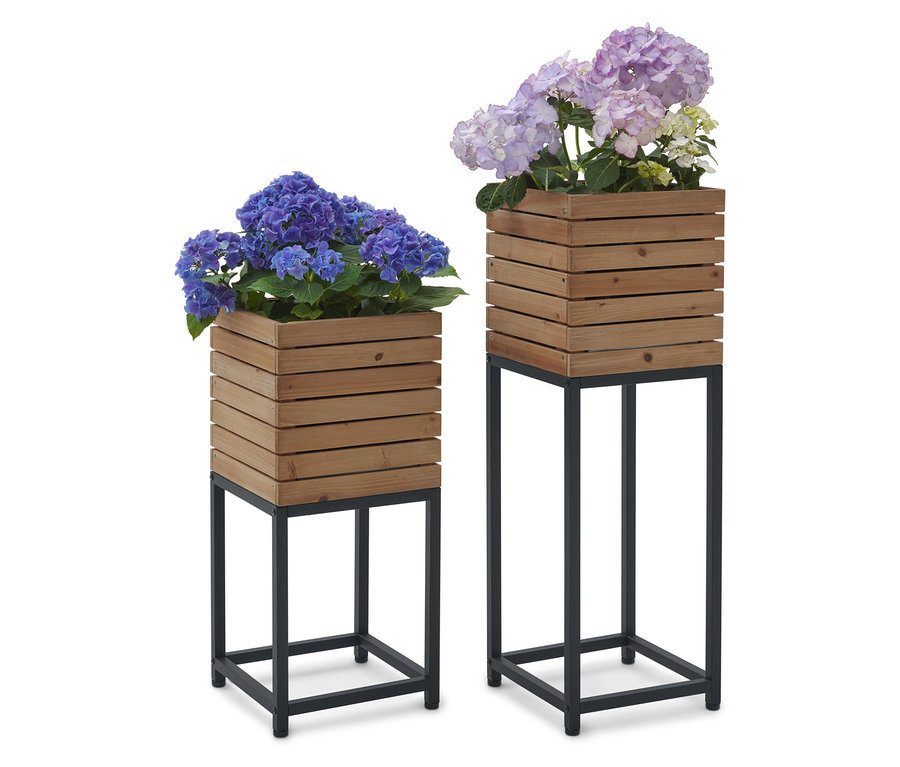 Zwei Blumenständer aus Holz mit blauen und lilafarbenen Hortensienblüten darauf.