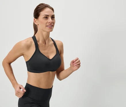 Frau beim Laufen, sie trägt einen schwarzen Sport-BH und Leggings.