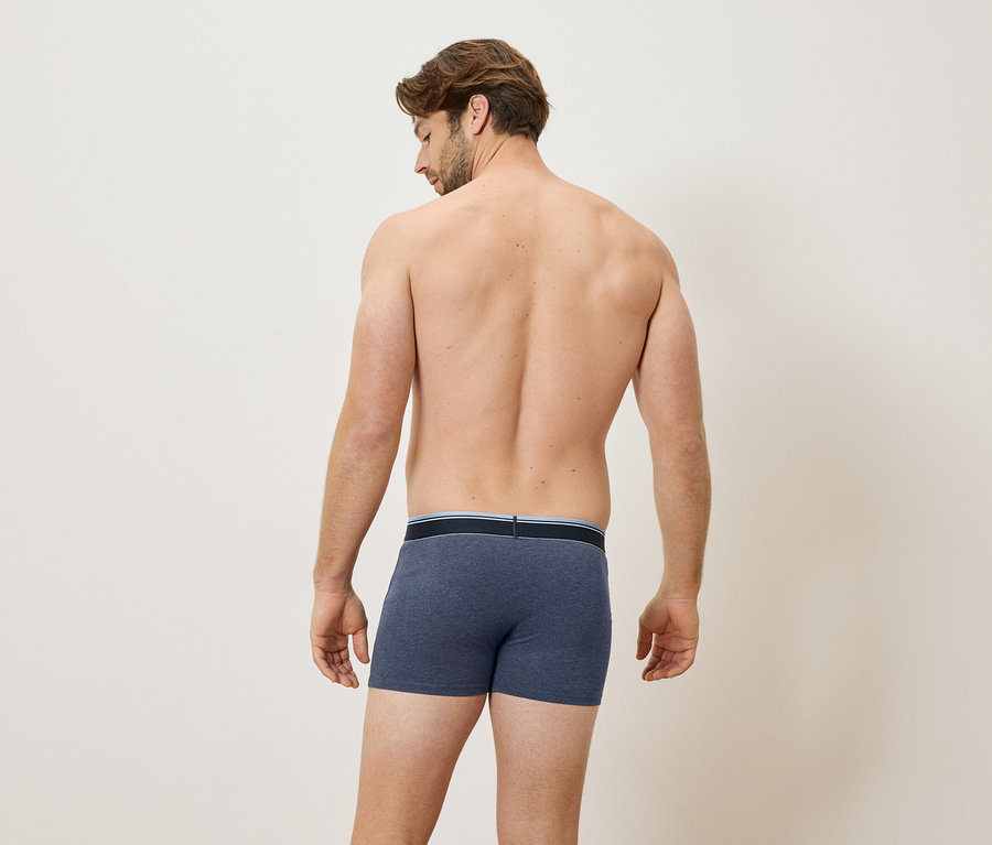 Mann von hinten, trägt blaue Boxershorts.