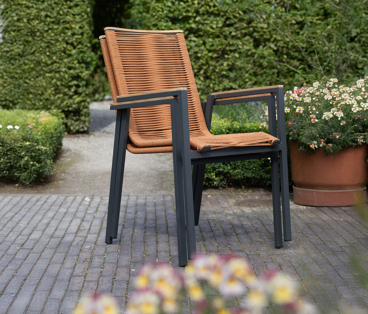 Ein brauner Sessel mit Armlehnen steht im Garten.