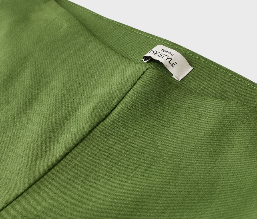 Detailansicht eines olivgrünen Kleidungsstücks mit einem Etikett, auf dem "TCHIBO MY STYLE" steht.