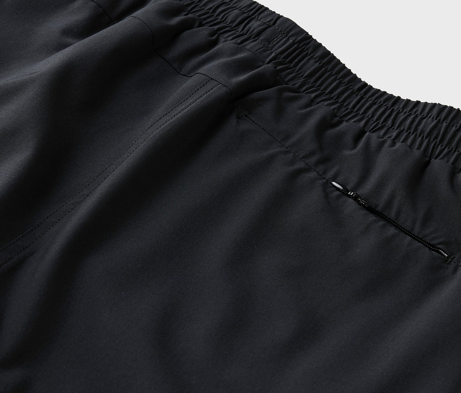 Detailaufnahme der Rückseite einer schwarzen Hose mit elastischem Bund und einer Reißverschlusstasche.